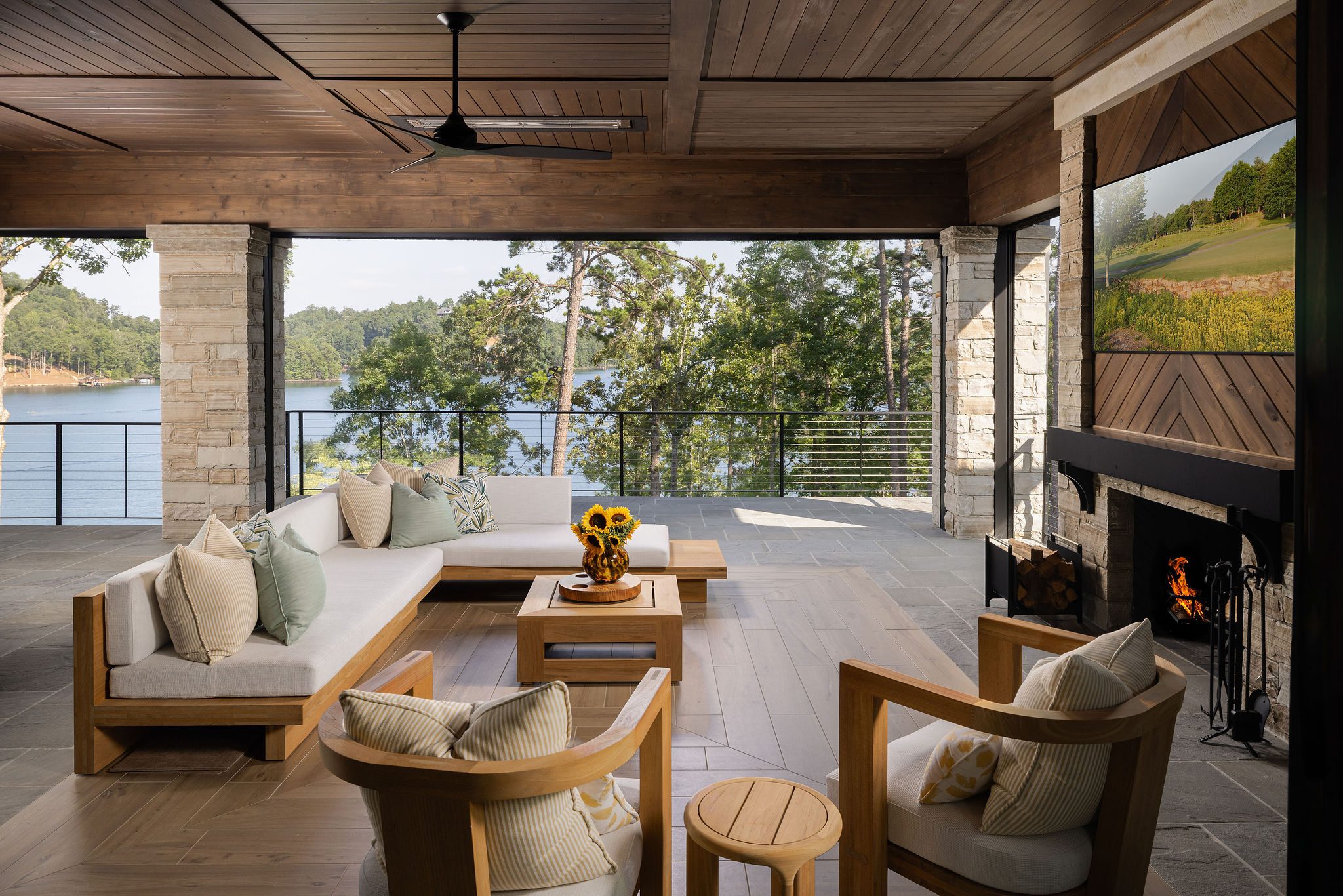 Lakefront covered porch with stone fireplace Gabriel Builders custom home