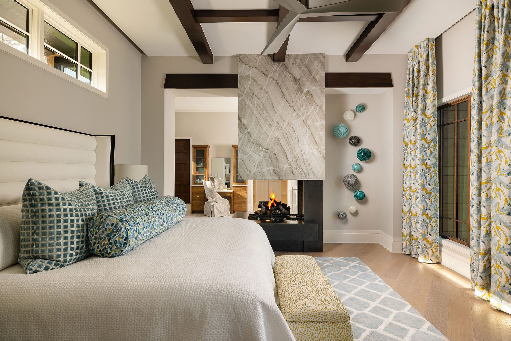 Gabriel Builders master suite with marble fireplace and exposed beams